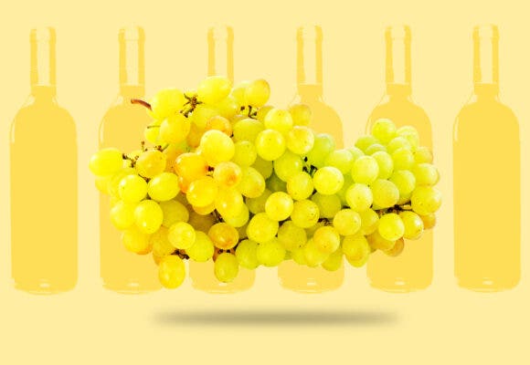 white wine grapes with 6 bottles of wine in the background