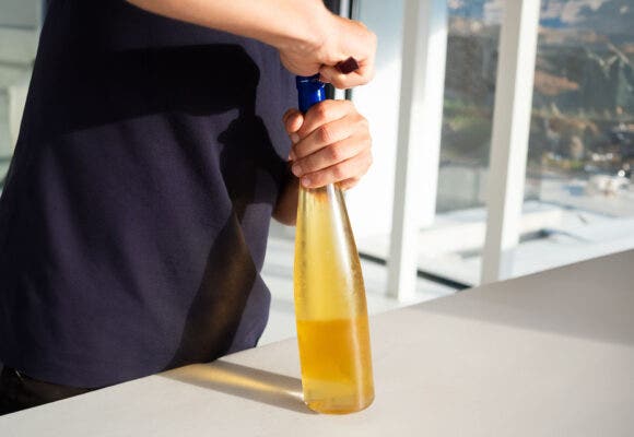Close up of an anonymous male person opening a bottle of white wine on his kitchen table. Detail of a person using a bottle opener to open a bottle of wine in his kitchen at home.